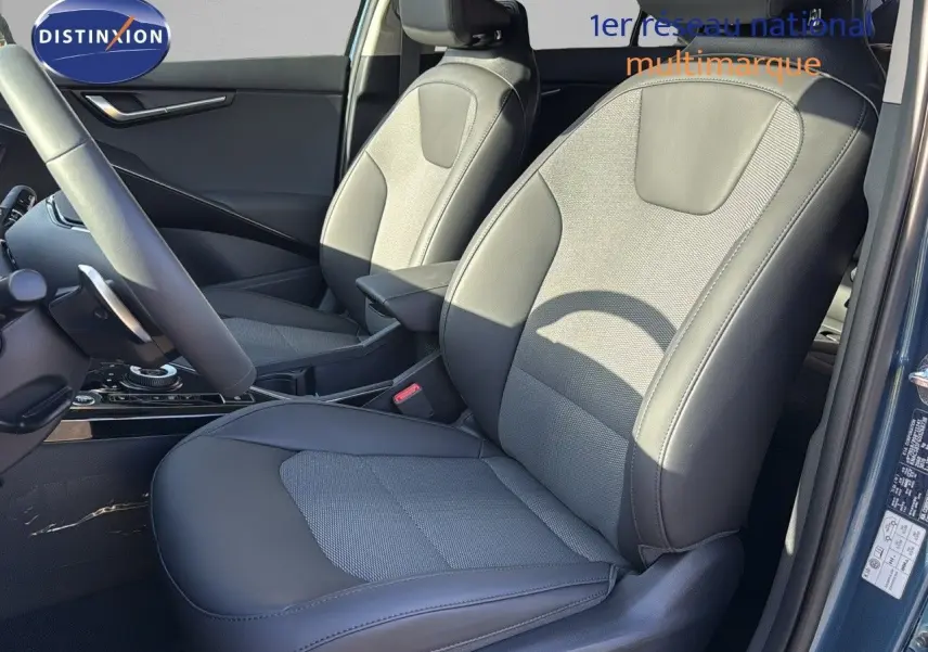 Vue intérieure rapprochée des sièges avant en cuir noir du Kia Niro 2025 bleu minéral métal, côté conducteur ouvert.