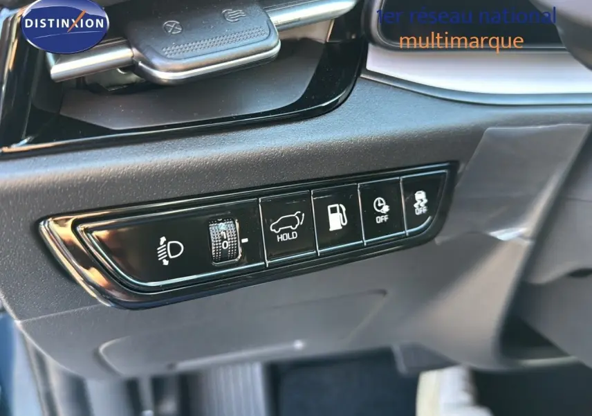 Gros plan sur les commandes noires du tableau de bord du Kia Niro bleu minéral 2025, côté conducteur.