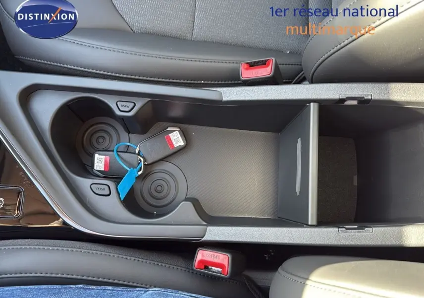 Gros plan sur la console centrale avec porte-gobelets et clés, intérieur cuir noir du Kia Niro 2025.