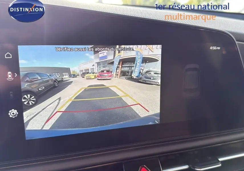 Écran tactile affichant la caméra de recul du Kia Niro bleu minéral, avec lignes de guidage et vue arrière du parking.
