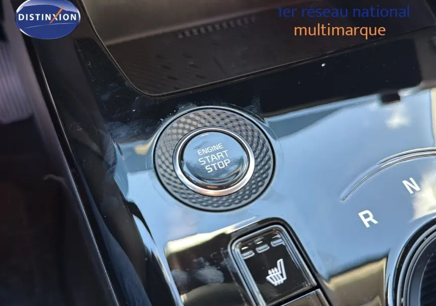 Gros plan sur la console centrale noire brillante du Kia Niro 2025, avec bouton start/stop et commande siège chauffant.