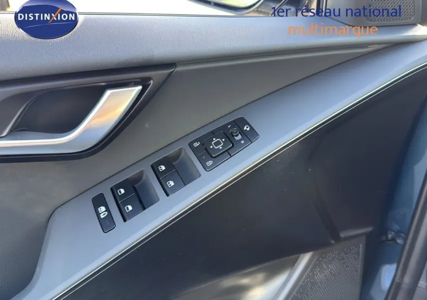 Panneau de porte côté conducteur du Kia Niro bleu minéral métal 2025 avec commandes de vitres et rétroviseurs.