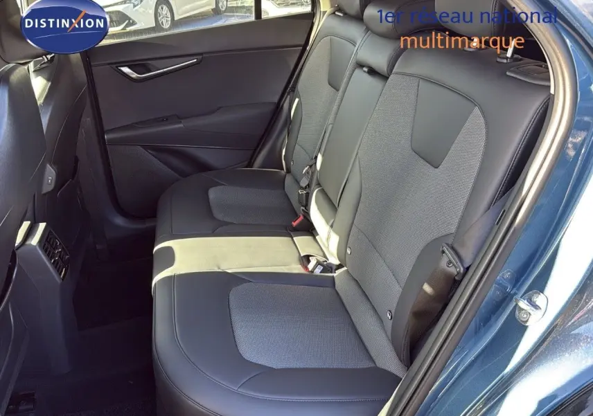 Intérieur arrière du Kia Niro 2025 bleu minéral métal, montrant les sièges en cuir noir et tissu gris côté droit.