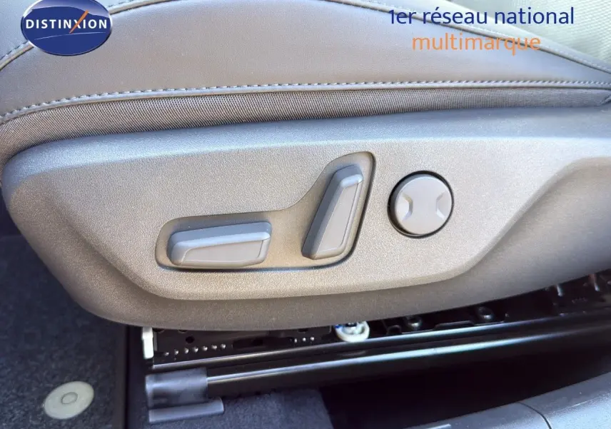 Gros plan sur les commandes électriques du siège conducteur en cuir gris du Kia Niro bleu minéral 2025.