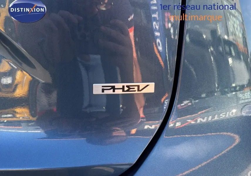 Gros plan sur l'emblème PHEV sur la porte arrière droite d'un Kia Niro bleu minéral métal 2025 hybride rechargeable.