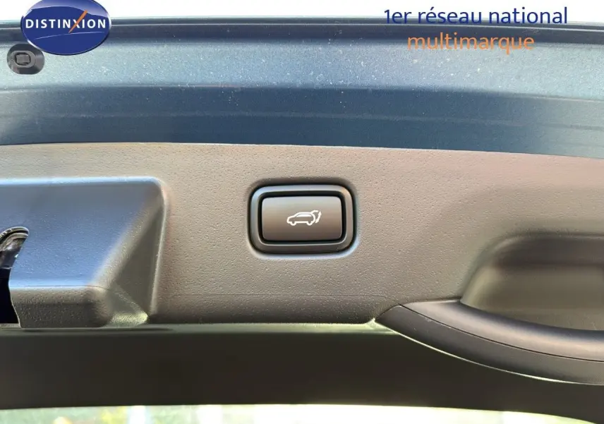 Bouton d'ouverture électrique du coffre sur la partie intérieure du hayon bleu minéral métal d'un Kia Niro 2025 hybride rechargeable.