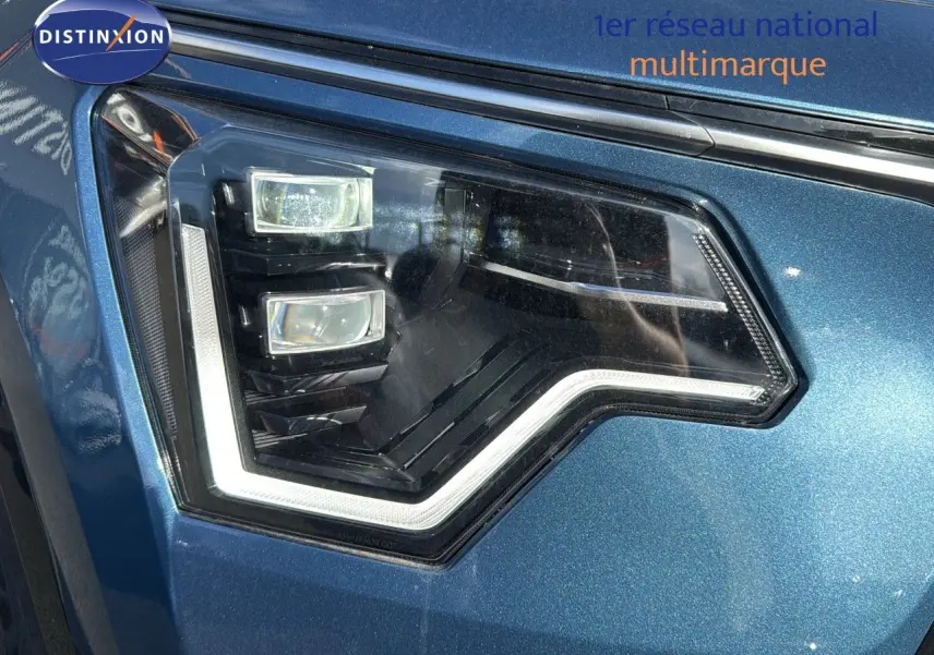 Gros plan sur le phare avant gauche du KIA NIRO 2025 en bleu minéral métal avec éclairage LED distinctif.