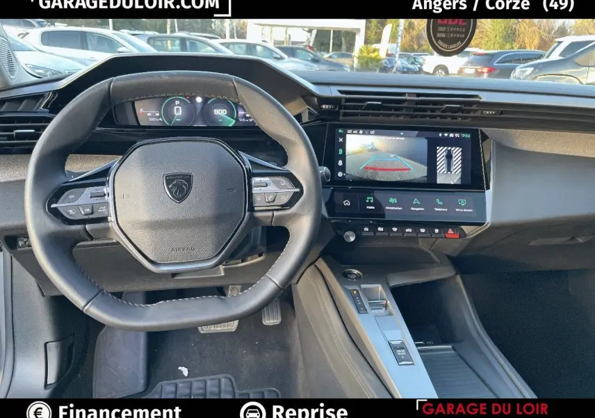 Intérieur Peugeot 308 2024, vue du poste de conduite avec volant compact et écran tactile affichant la caméra de recul.