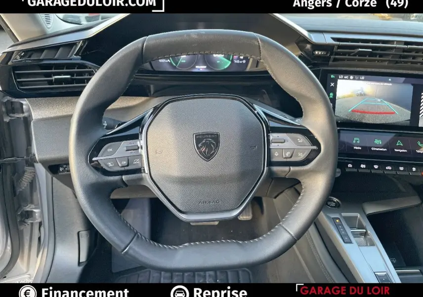 Vue intérieure du volant cuir noir et tableau de bord numérique de la Peugeot 308 Gris Artense 2024 avec écran tactile et caméra de recul.