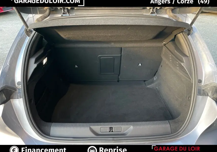 Coffre ouvert d'une Peugeot 308 gris Artense vue de l'arrière, montrant un espace de chargement propre et spacieux.