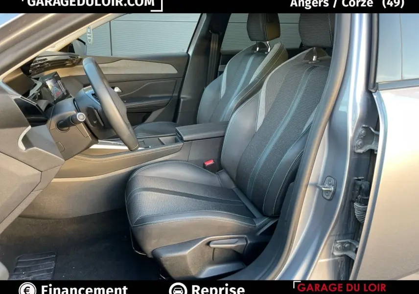 Intérieur côté conducteur de la Peugeot 308 gris Artense 2024, sièges bi-matière avec surpiqûres bleues et tableau de bord moderne.