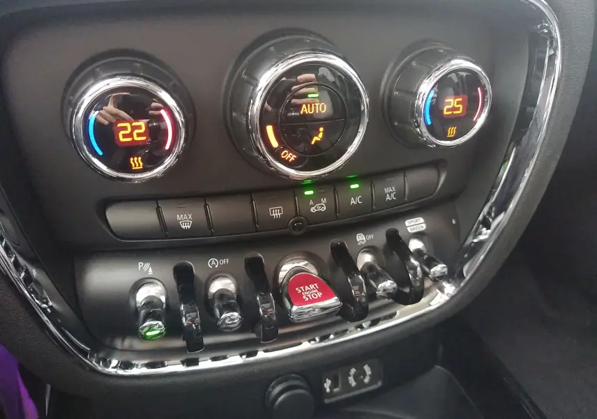 Gros plan sur la console centrale de la MINI Clubman F54 2017 avec commandes de climatisation et bouton rouge Start/Stop.
