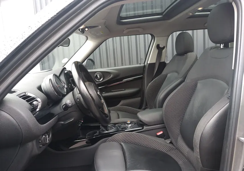 Intérieur noir de la MINI CLUBMAN F54 2017, vue côté conducteur avec volant, sièges en cuir et toit ouvrant panoramique.