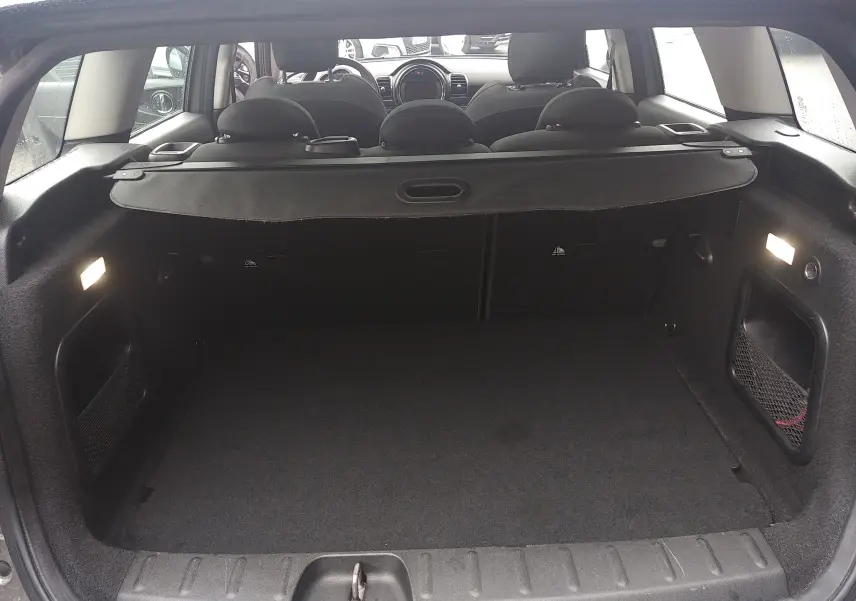 Coffre ouvert d'une MINI CLUBMAN F54 Silver Metal, vue arrière intérieure montrant l'espace de chargement et les sièges noirs.