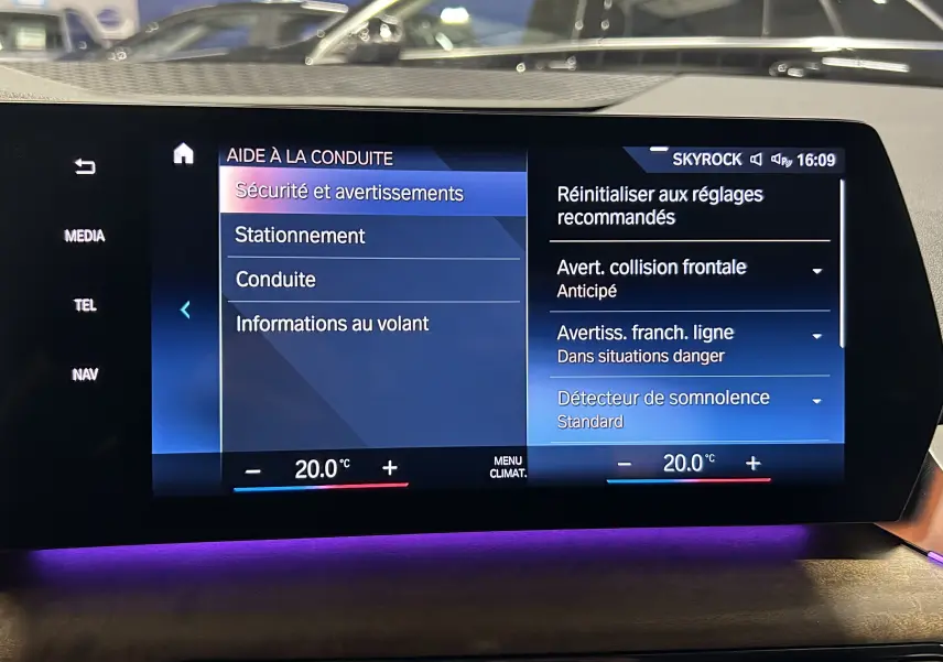 Écran tactile central de la BMW Série 2 Active Tourer blanc, affichant les options d'aide à la conduite et la climatisation à 20°C.