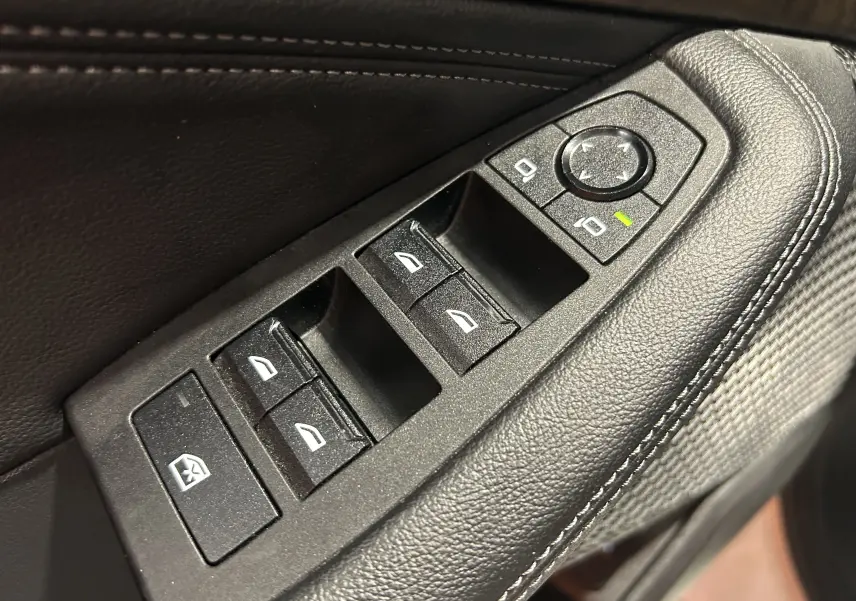 Gros plan sur les commandes de lève-vitres et réglage des rétroviseurs côté conducteur en cuir noir sur BMW Série 2 Active Tourer.