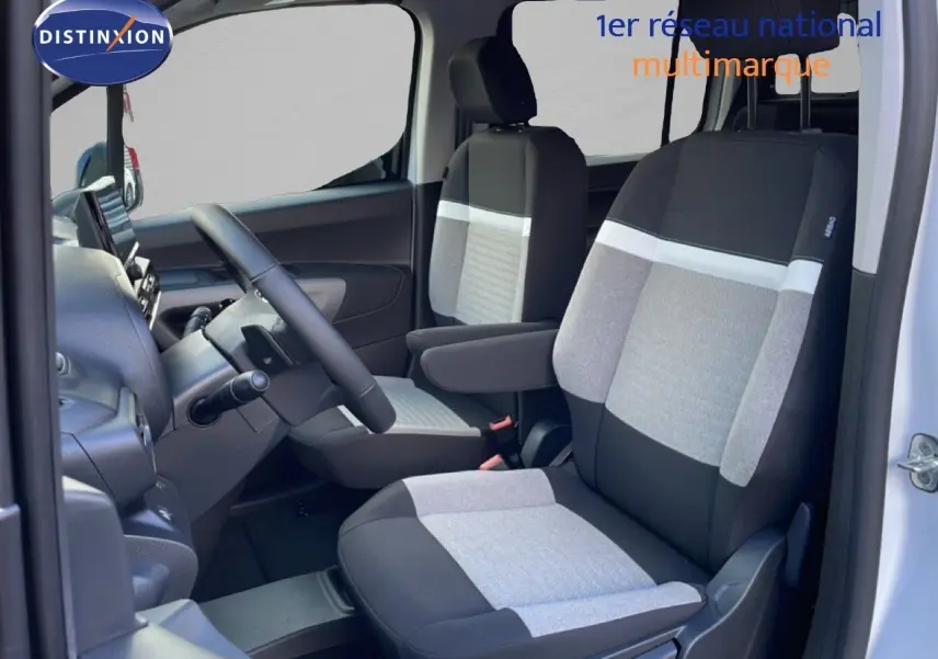 Vue intérieure côté conducteur du Citroën Berlingo blanc glacier 2025, sièges tissu bicolore gris et noir avec accoudoirs.