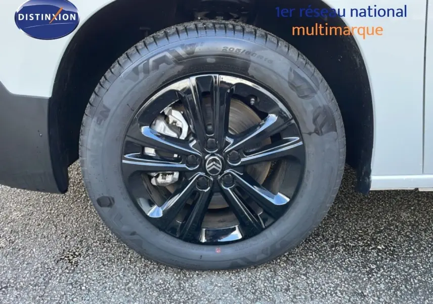 Gros plan sur la roue avant gauche d’un Citroën Berlingo blanc glacier avec jante noire brillante.