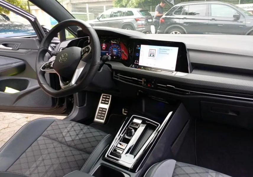 Vue intérieure côté conducteur de la Volkswagen Golf 1.5 eTSI 2024, tableau de bord numérique et volant cuir multifonctions.