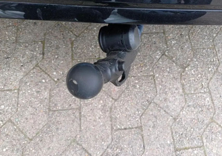 Gros plan sur l'attelage escamotable noir sous le pare-chocs arrière de la Volkswagen Golf 1.5 eTSI noire.