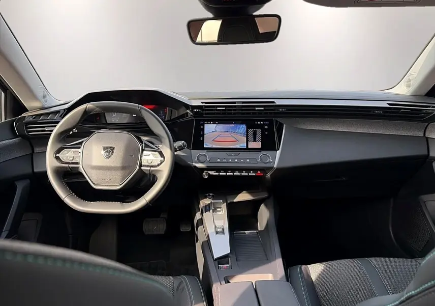 Vue intérieure avant de la Peugeot 308 noire 2025, avec volant multifonction et écran tactile affichant la caméra de recul.
