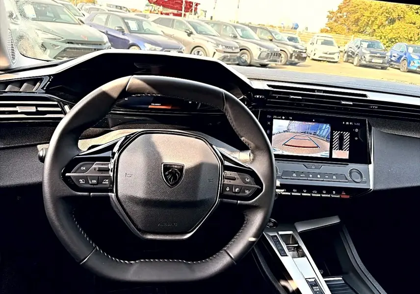 Vue intérieure centrée sur le volant Peugeot noir et l'écran tactile affichant la caméra de recul.