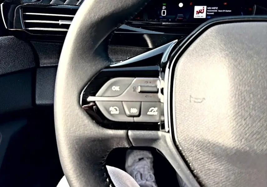 Gros plan sur le volant noir multifonction de la Peugeot 308 2025 avec commandes intégrées côté gauche.