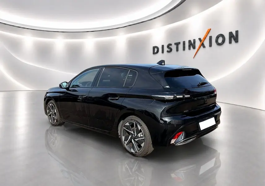 Peugeot 308 noire vue 3/4 arrière droit dans un showroom lumineux avec jantes alliage et vitres surteintées.