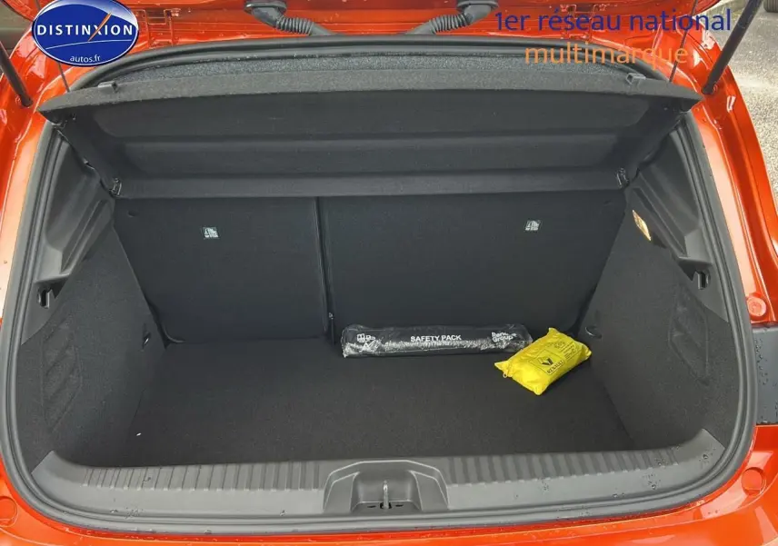 Coffre ouvert d'une Renault Clio V orange Valencia, montrant un espace de rangement avec kit de sécurité noir et jaune.