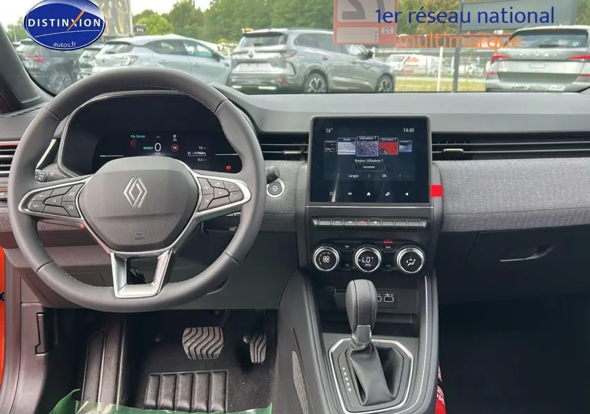 Intérieur avant de la Renault Clio V orange Valencia, volant multifonction et écran tactile central visible.