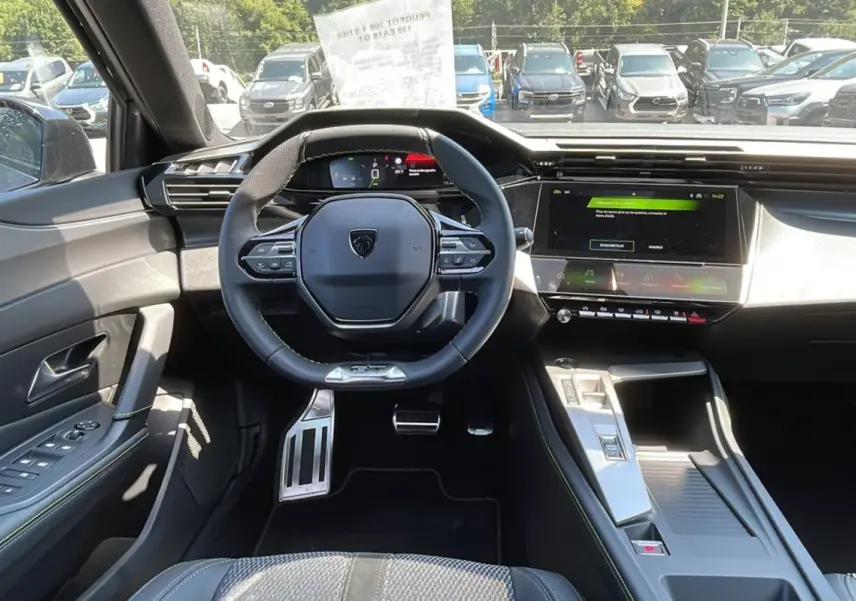 Intérieur moderne de la Peugeot 308 2025, vue du poste de conduite avec volant compact et écran tactile central.