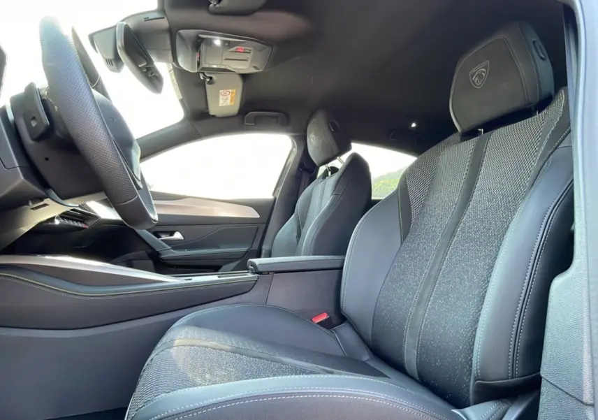 Intérieur de la Peugeot 308 2025, vue côté gauche sur les sièges avant en cuir noir avec logo GT brodé sur les appuie-têtes