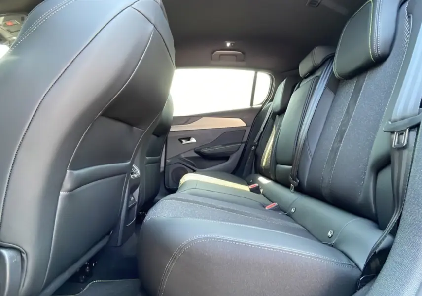 Vue latérale droite de l'intérieur arrière de la Peugeot 308 2025 gris selenium, sièges en cuir noir avec surpiqûres blanches.