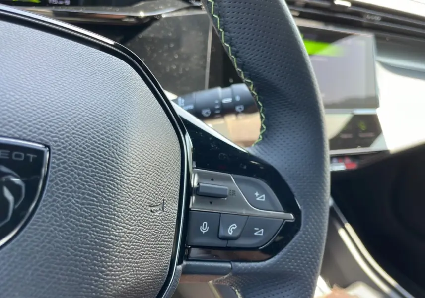 Gros plan sur le volant cuir perforé avec surpiqûres vertes de la Peugeot 308 1.5 HDI 130 EAT8 GT 2025.