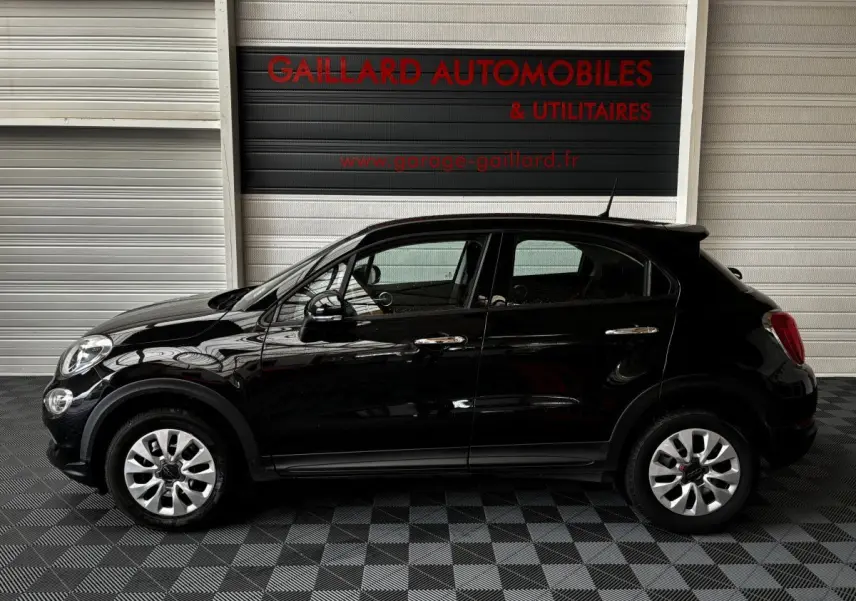 Vue latérale droite d'une FIAT 500X noire de 2018, compacte et élégante, avec jantes argentées et poignées chromées.