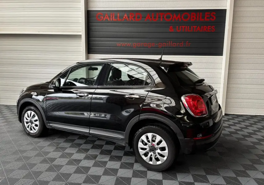 Vue 3/4 arrière droite d'une FIAT 500X noire 2018, avec jantes argentées et détails chromés sur les poignées.