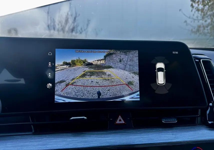 Écran tactile du Kia Sportage 2023 montrant la caméra de recul avec lignes de guidage sur fond noir intérieur.