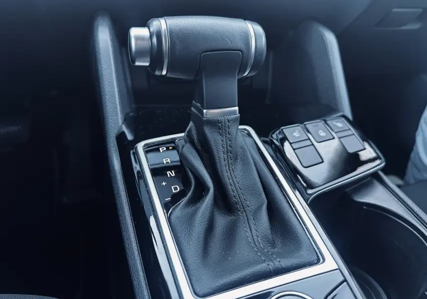 Le levier de vitesse automatique noir du Kia Sportage 2023, vue rapprochée de la console centrale avec boutons de contrôle.