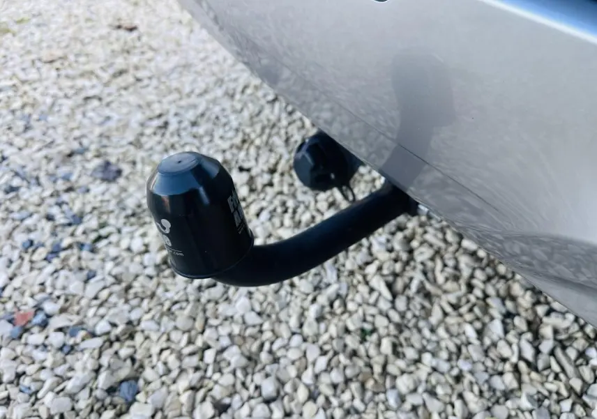 Gros plan sur l'attelage noir fixé à l'arrière d'un Kia Sportage noir, avec fond de gravier clair.