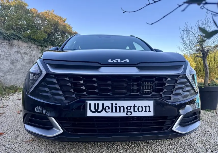 Vue frontale rapprochée du Kia Sportage noir 2023 avec calandre hexagonale et logo Kia lumineux.