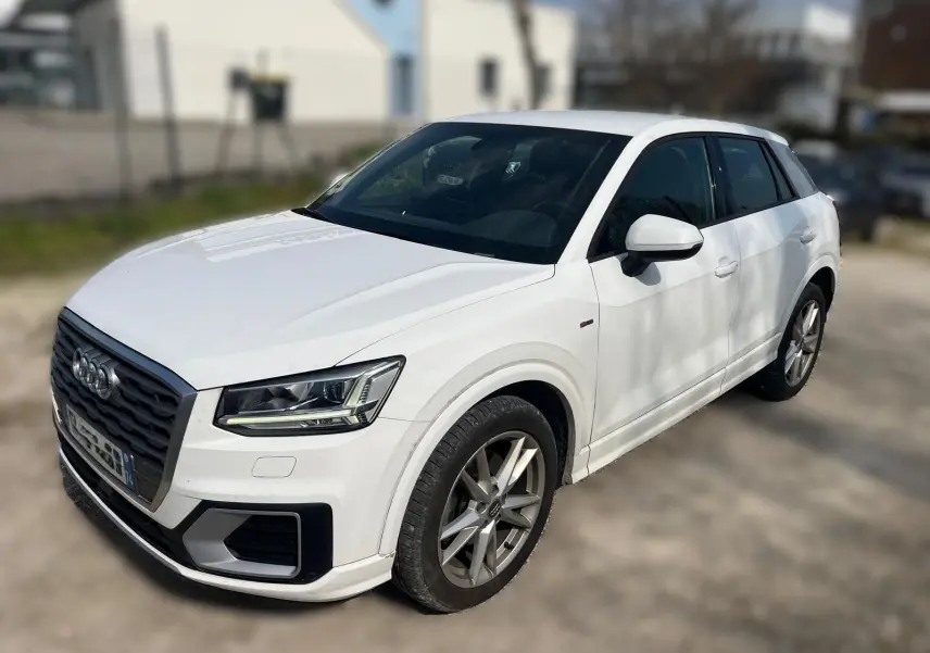 Audi Q2 blanc vue 3/4 avant droit, avec jantes alliage et calandre noire distinctive S-Line.