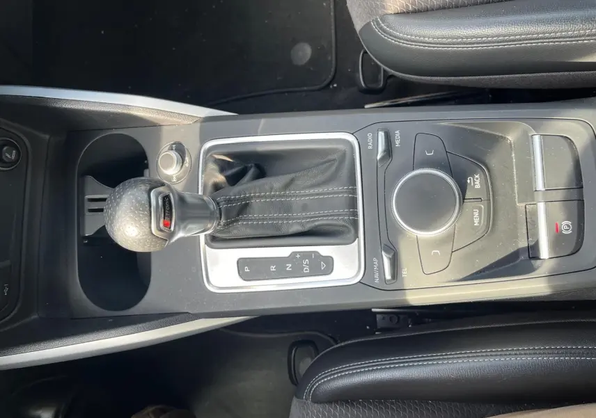 Vue rapprochée de la console centrale noire de l'Audi Q2 2018 avec levier de vitesse S-Tronic et commandes multimédia.