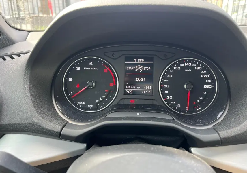 Vue rapprochée du tableau de bord noir de l'Audi Q2 blanc, avec compte-tours, compteur de vitesse et écran central digital.