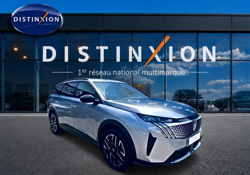 Peugeot 5008 Hybrid 145 gris Artense en 3/4 avant droit, avec calandre distinctive et jantes alu noires.