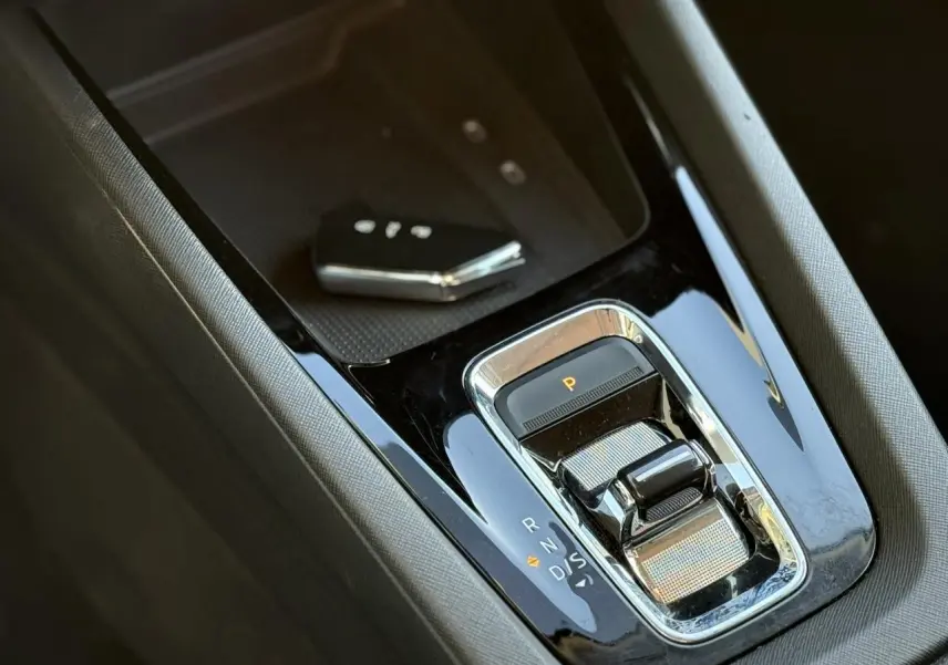 Gros plan sur la console centrale noire brillante de la Skoda Octavia Combi 2022 avec levier de boîte auto et clé main-libre.