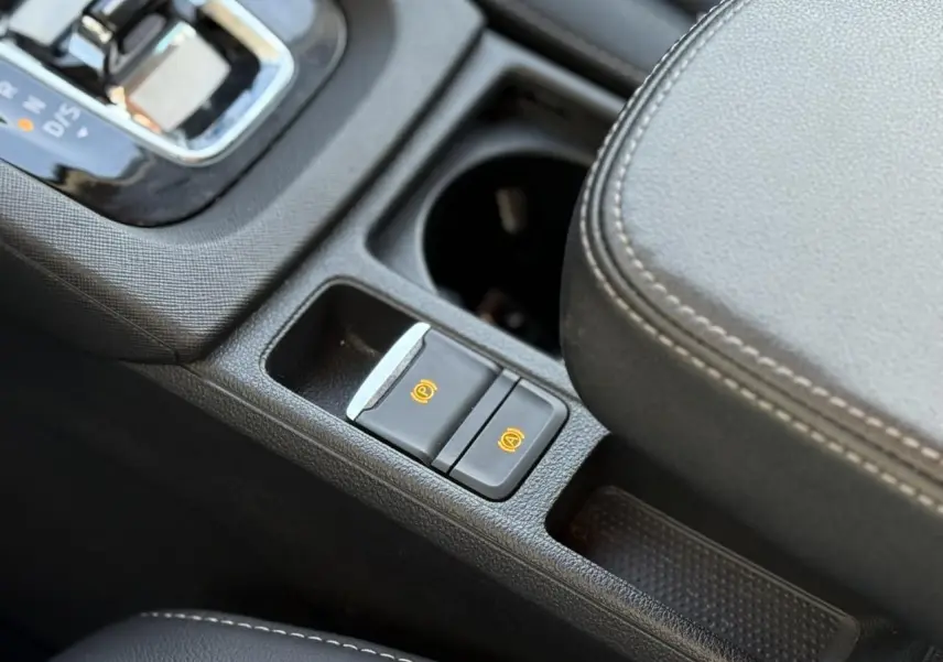 Gros plan sur la console centrale de la Skoda Octavia Combi 2022, montrant frein à main électrique et accoudoir en cuir noir.