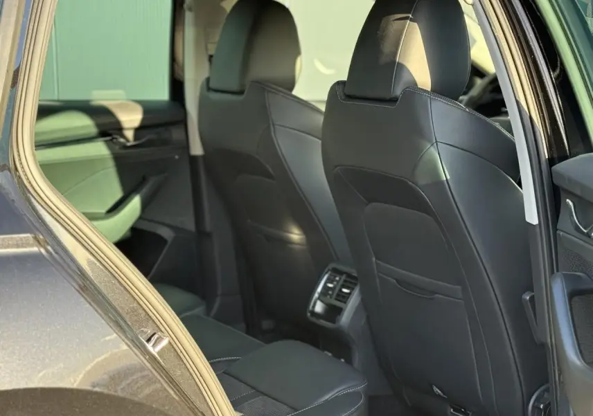 Vue intérieure arrière côté gauche d'une Skoda Octavia Combi noire 2022 avec sièges cuir noirs et aérateurs centraux.