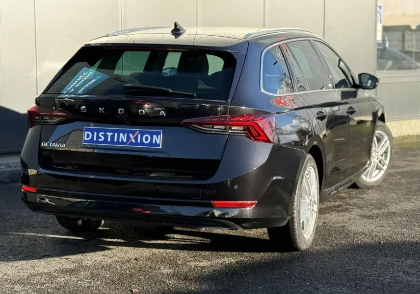 Vue 3/4 arrière droite d'une Skoda Octavia Combi noire avec feux arrière LED et hayon électrique visible.