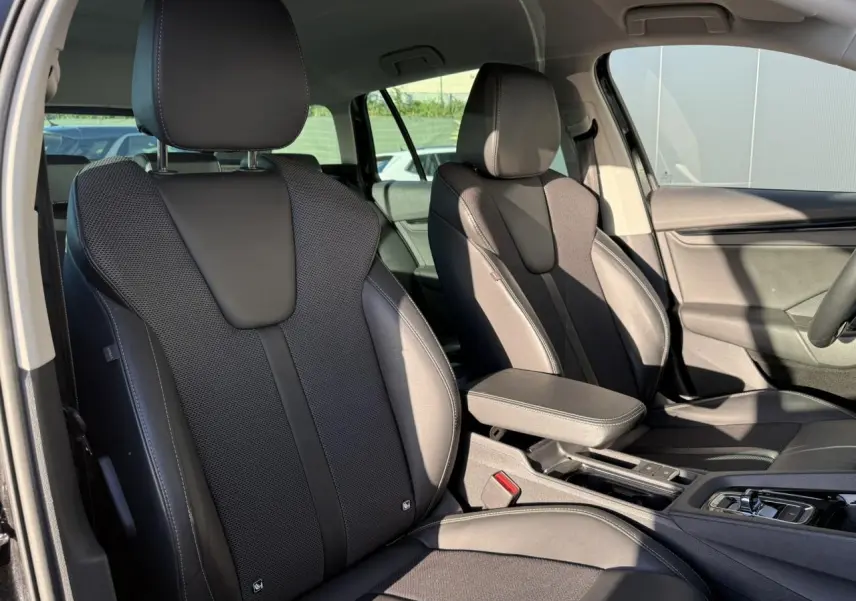 Vue intérieure sur les sièges avant en cuir/tissu noir de la Skoda Octavia Combi 2022 avec accoudoir central et console.