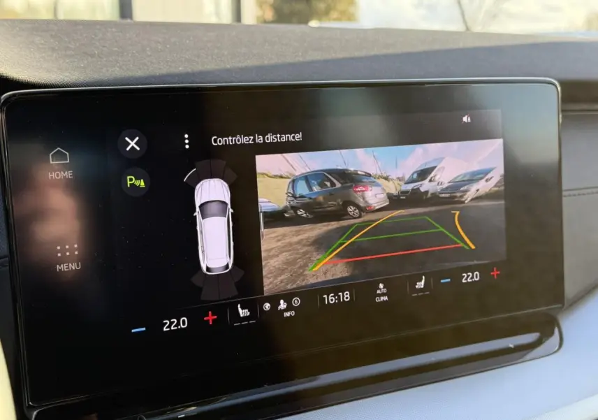 Écran multimédia affichant la caméra de recul d'une Skoda Octavia Combi noire avec lignes de guidage colorées.